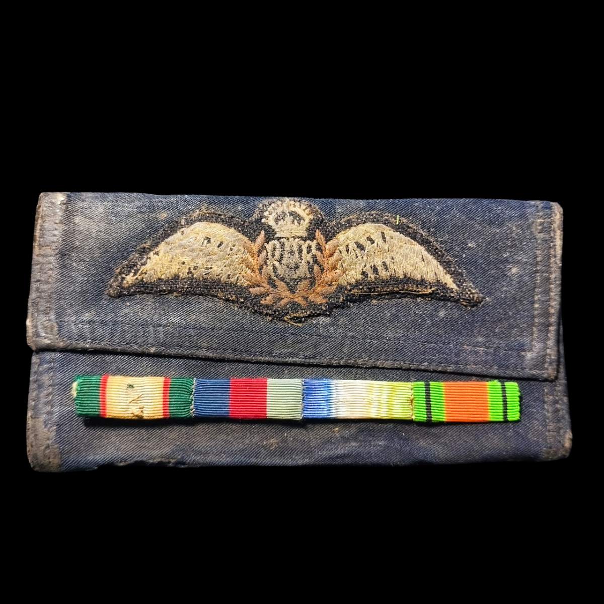 Original RAF navigator wings wallet with mounted ribbon bar from WWII medal group to J.C. Elphick, showing service wear.